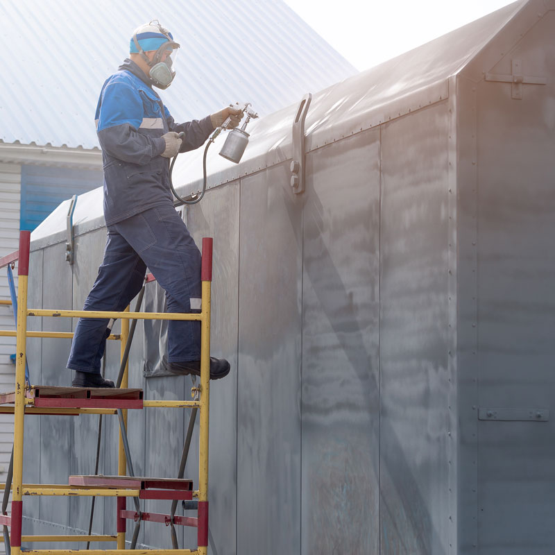 man spraying metal container